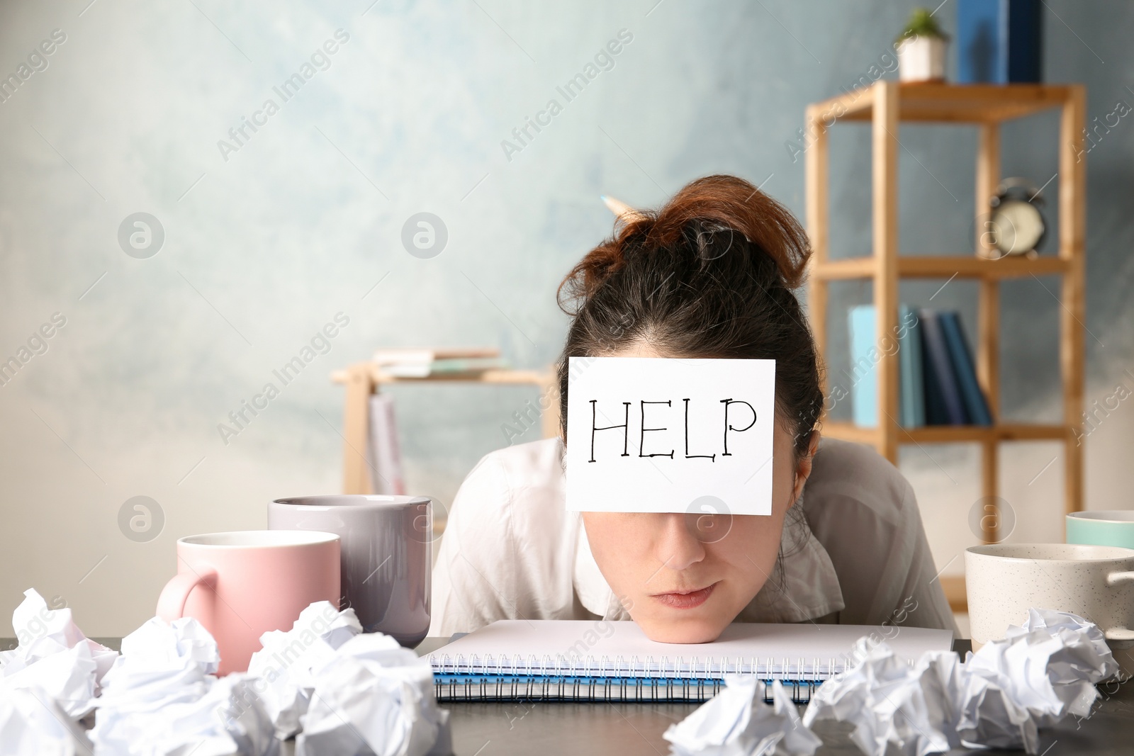Photo of Young woman with note HELP on forehead at workplace. Space for text