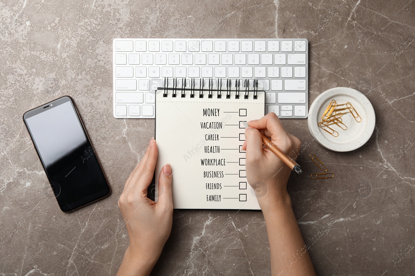 Image of Work-life balance concept. Woman writing in notebook at grey marble table, top view