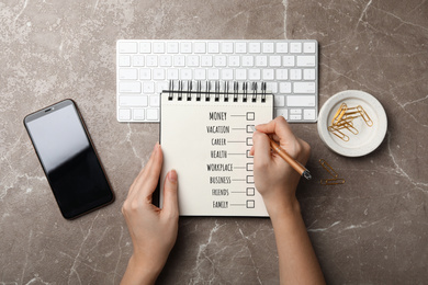 Work-life balance concept. Woman writing in notebook at grey marble table, top view