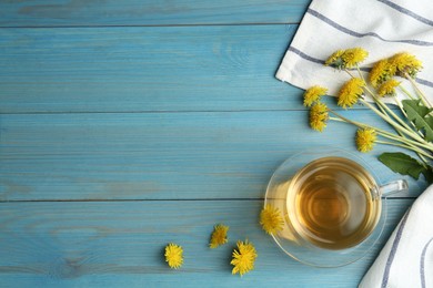 Delicious tea and dandelion flowers on light blue wooden table, flat lay. Space for text