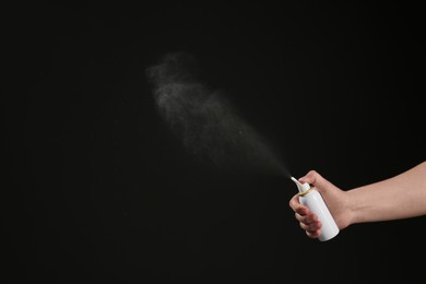 Photo of Nasal congestion. Woman spraying remedy from bottle on black background, closeup with space for text