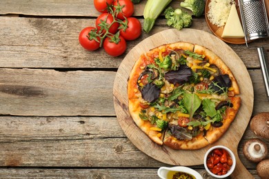 Photo of Delicious vegetarian pizza and ingredients on wooden table, flat lay. Space for text