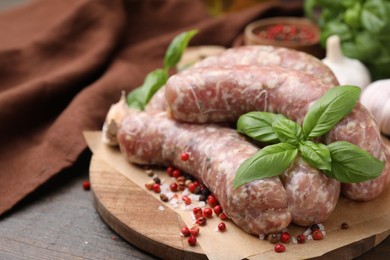 Photo of Raw homemade sausages and different spices on wooden table, closeup. Space for text