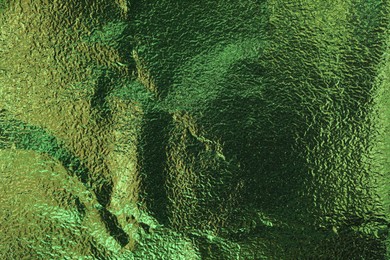 Textured green foil as background, top view
