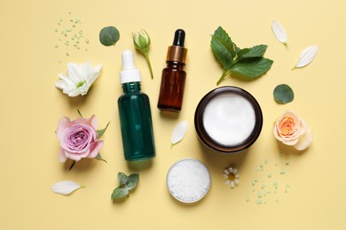 Flat lay composition with cosmetic serums on pale yellow background