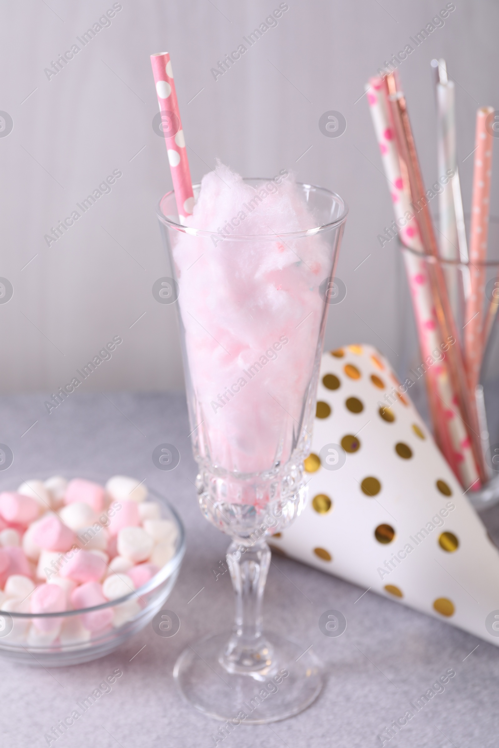 Photo of Tasty cotton candy cocktail in glass, festive decor and marshmallows on gray table