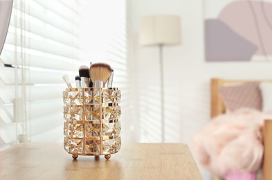 Set of professional makeup brushes on wooden table in teenager's room. Space for text