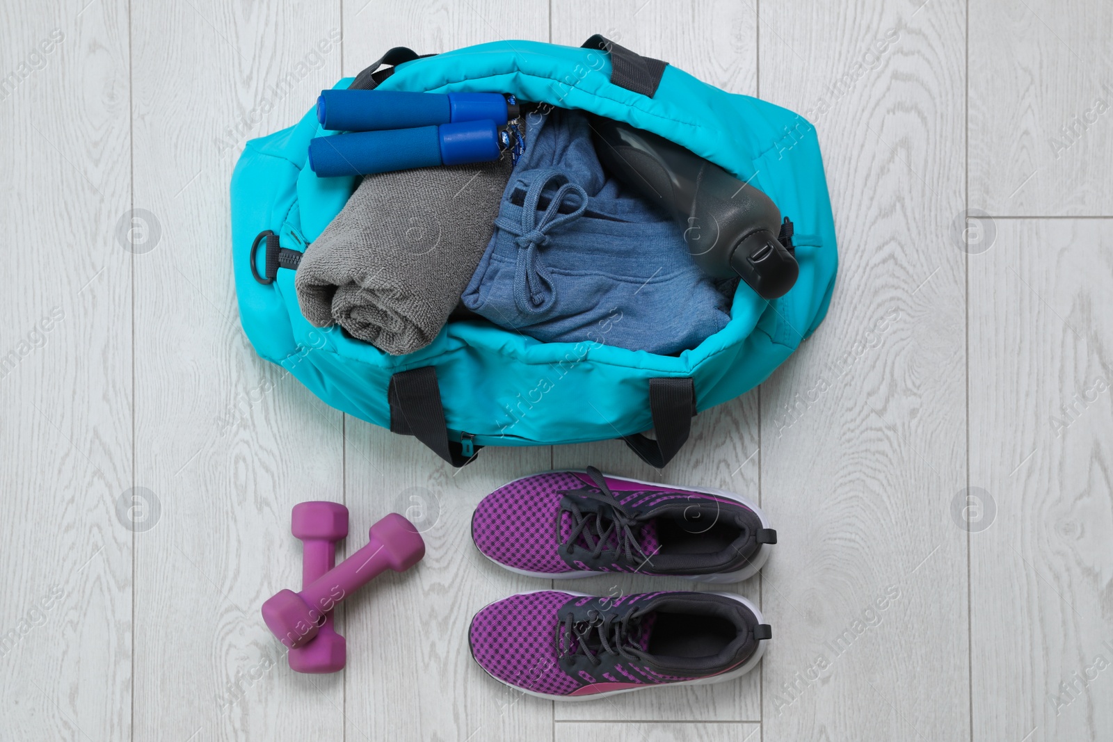 Photo of Bag with different sports equipment on wooden floor, flat lay