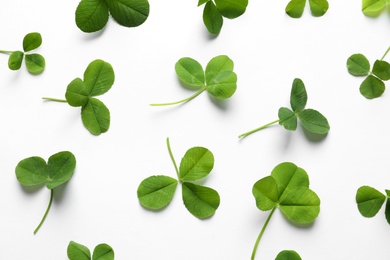 Flat lay composition with green clover leaves on white background, top view