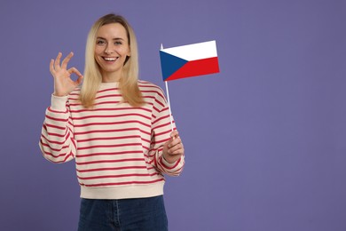 Happy young woman with flag of Czech republic showing OK gesture on purple background