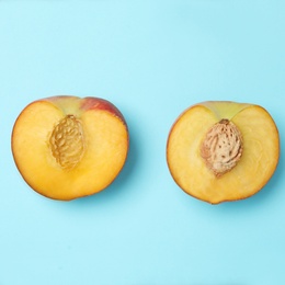 Photo of Halves of sweet juicy peach on light blue background, top view