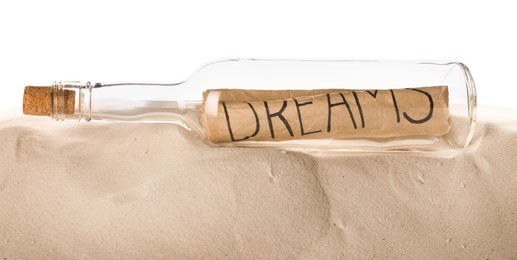 Photo of Corked glass bottle with Dreams note on sand against white background