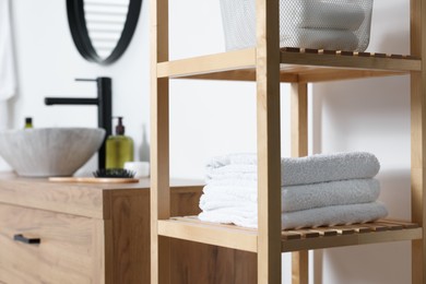 Photo of Stacked bath towel on wooden shelf indoors. Space for text