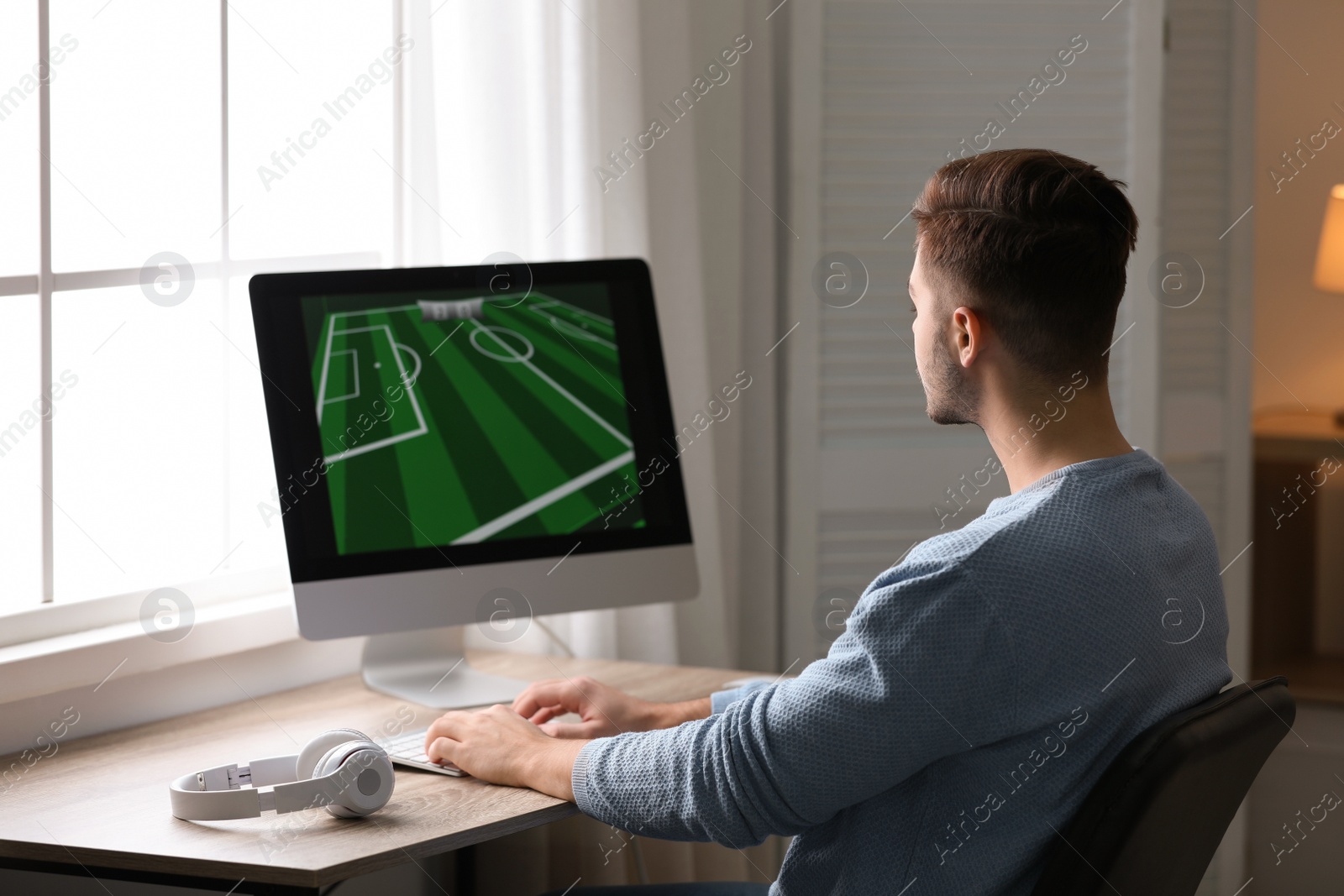 Photo of Young man playing video games at home