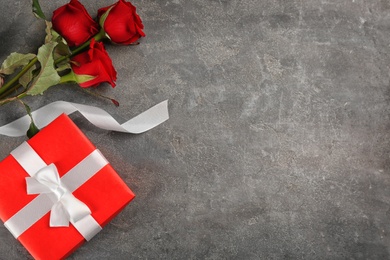 Photo of Beautiful red roses and gift box on grey background, flat lay with space for text. Valentine's Day celebration