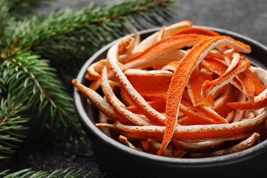 Photo of Dry orange peels and fir branch on gray textured table, closeup