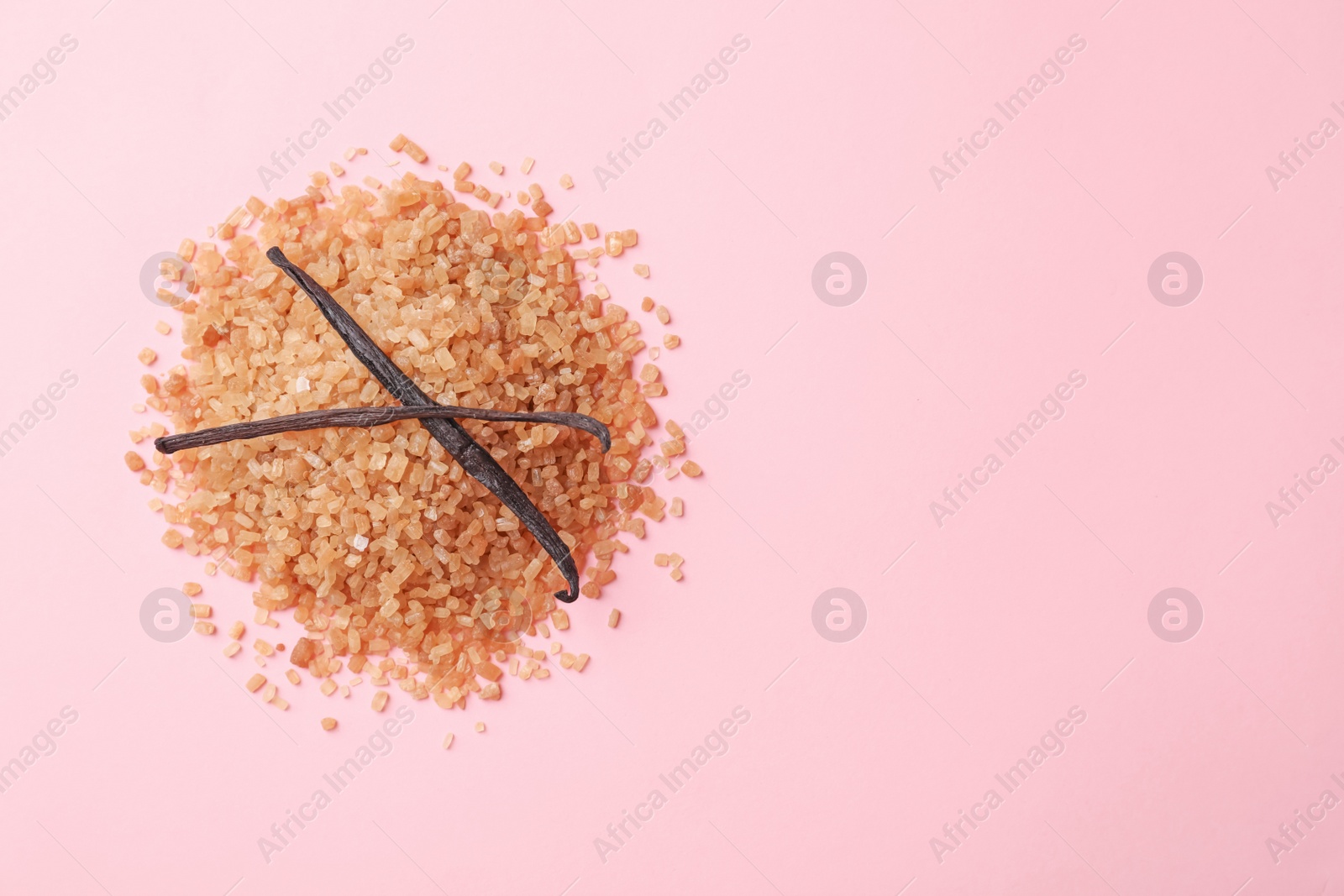 Photo of Pile of brown vanilla sugar on color background, top view