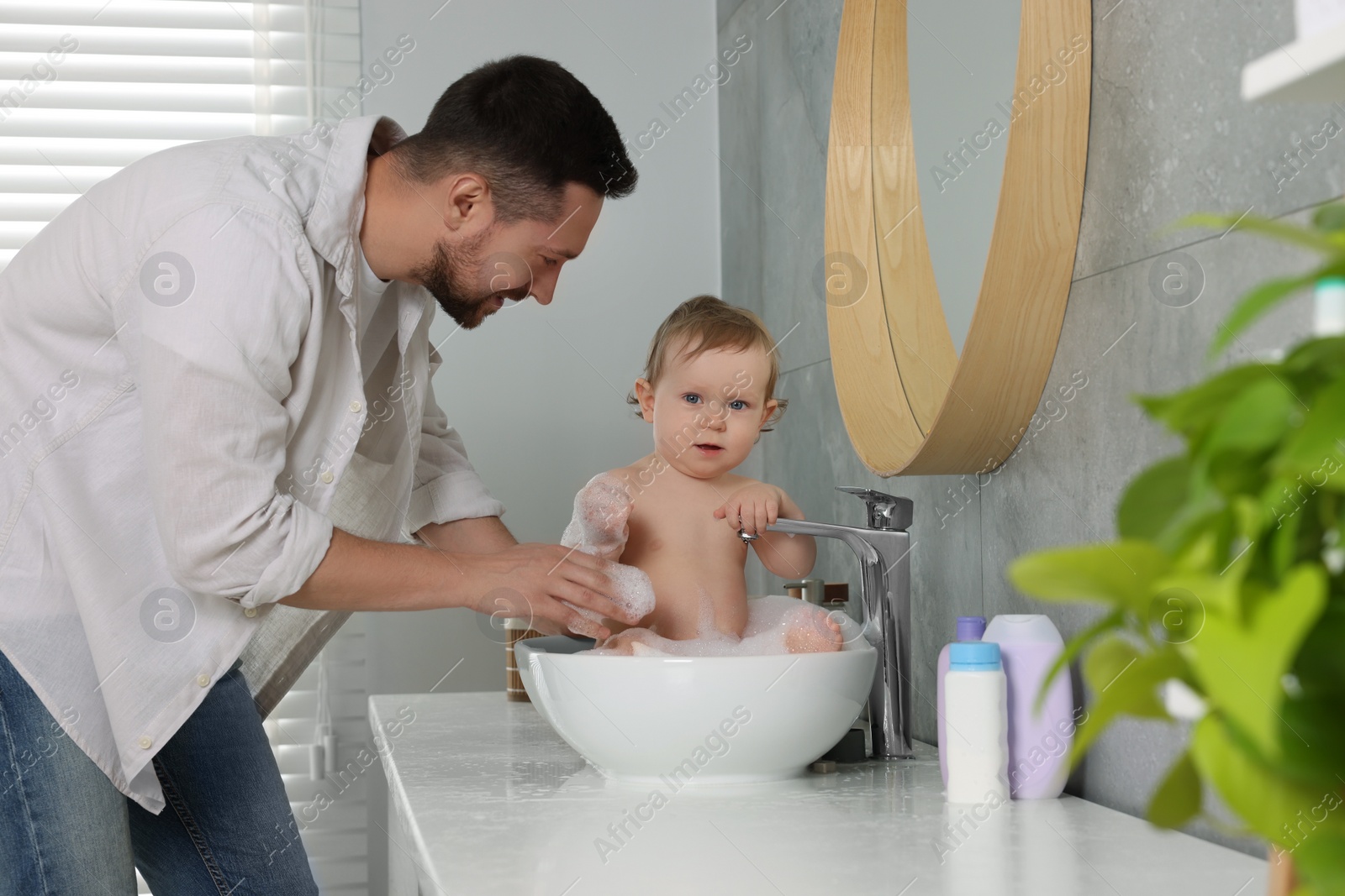 Photo of Father washing his little baby in sink at home