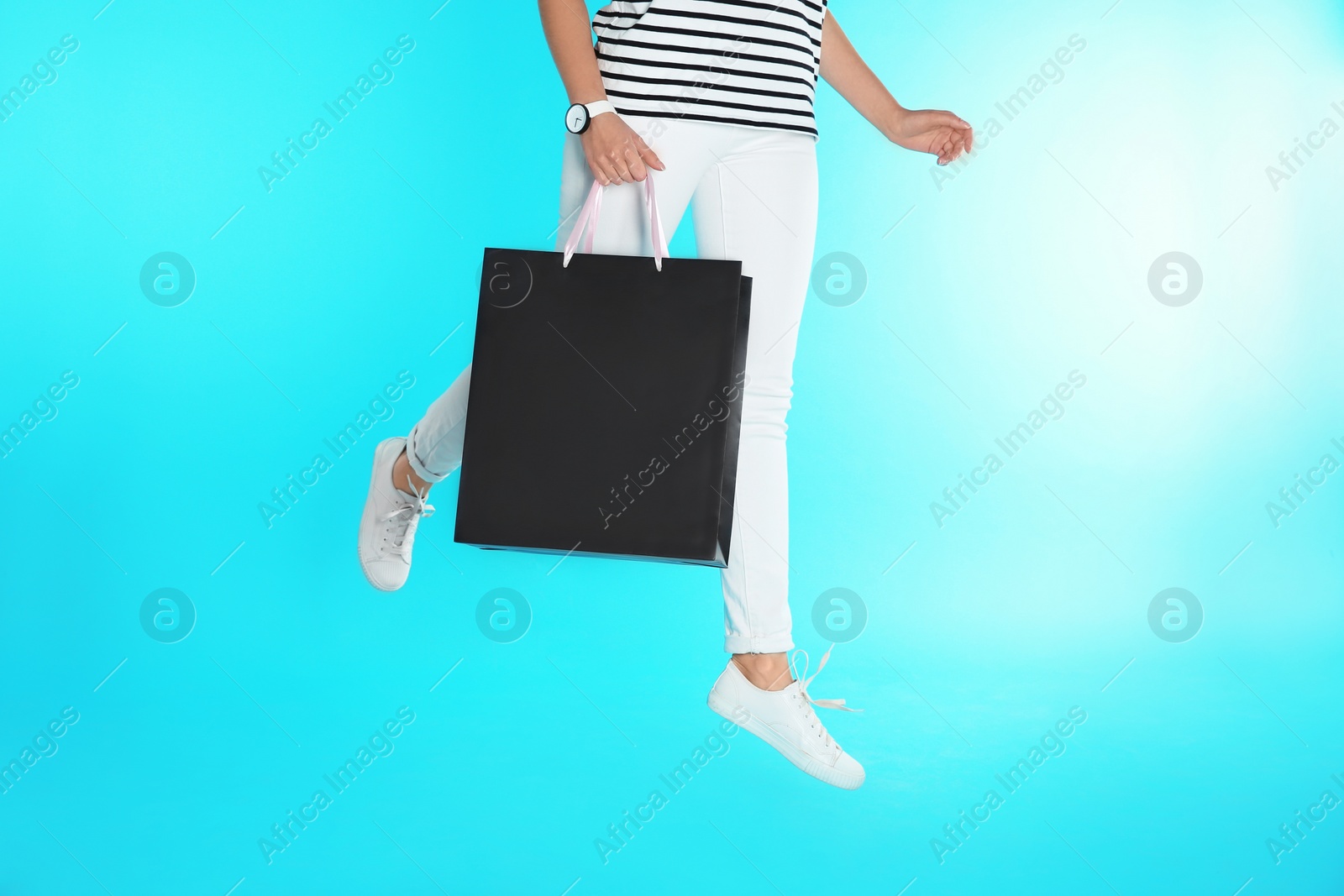 Photo of Woman jumping with paper shopping bag on color background. Mock up for design