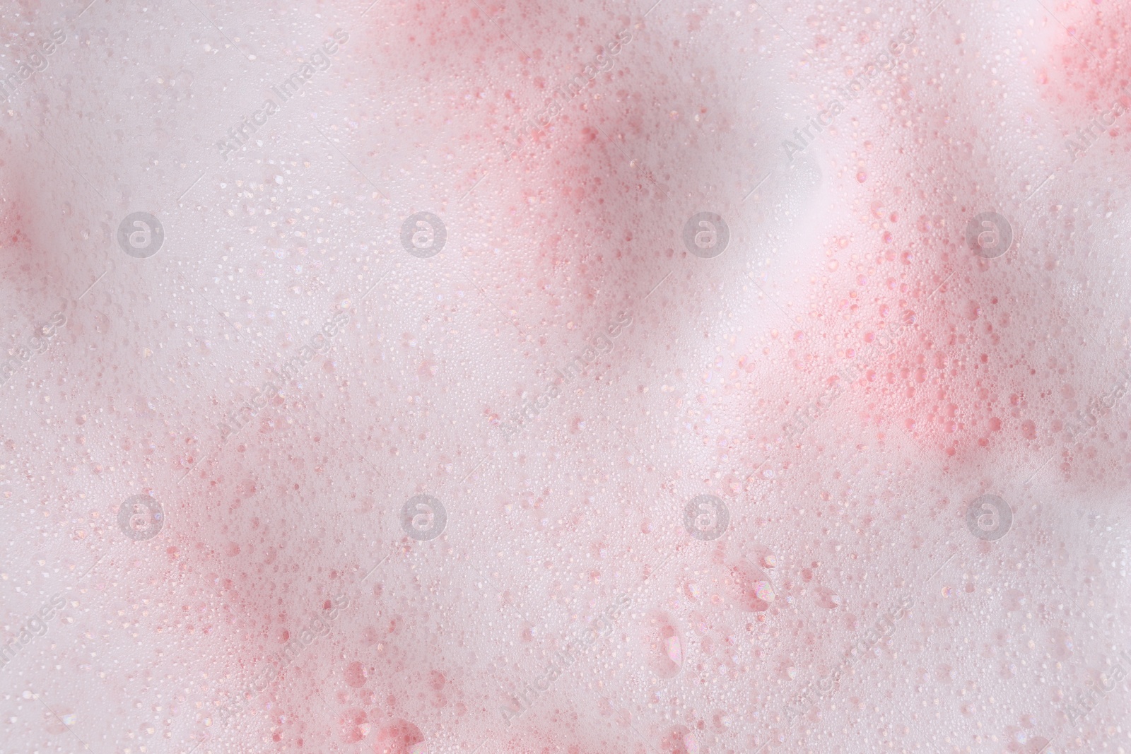 Photo of White fluffy foam on pink background, top view