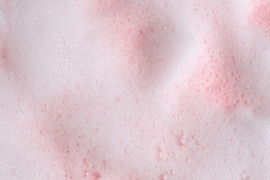 Photo of White fluffy foam on pink background, top view