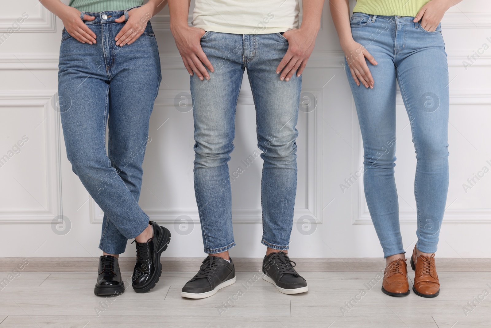 Photo of People in stylish jeans near white wall indoors, closeup