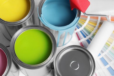 Photo of Cans of paints, roller and palette on white background, above view