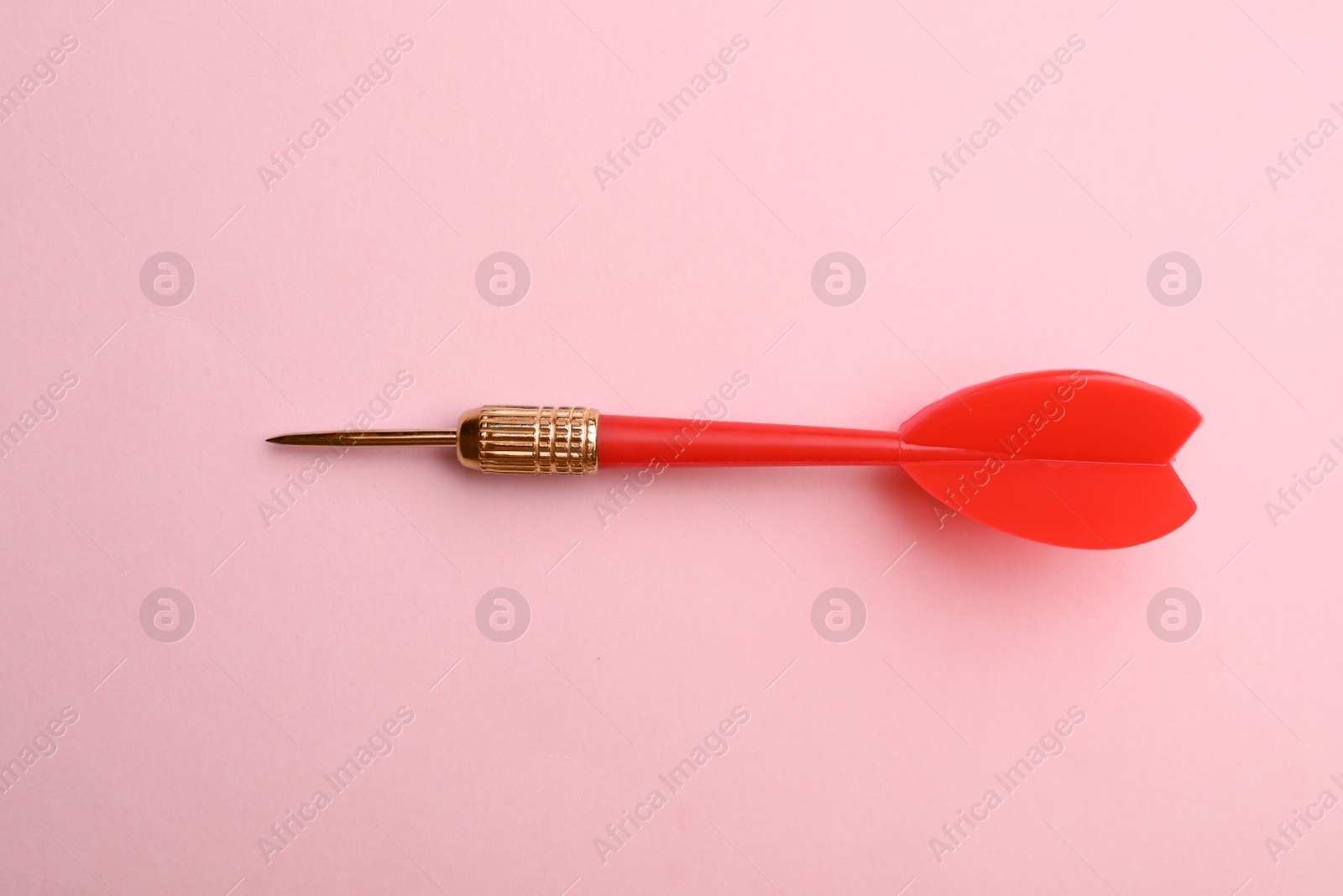 Photo of Red dart arrow on pink background, top view