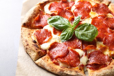 Tasty pepperoni pizza with basil on table, closeup