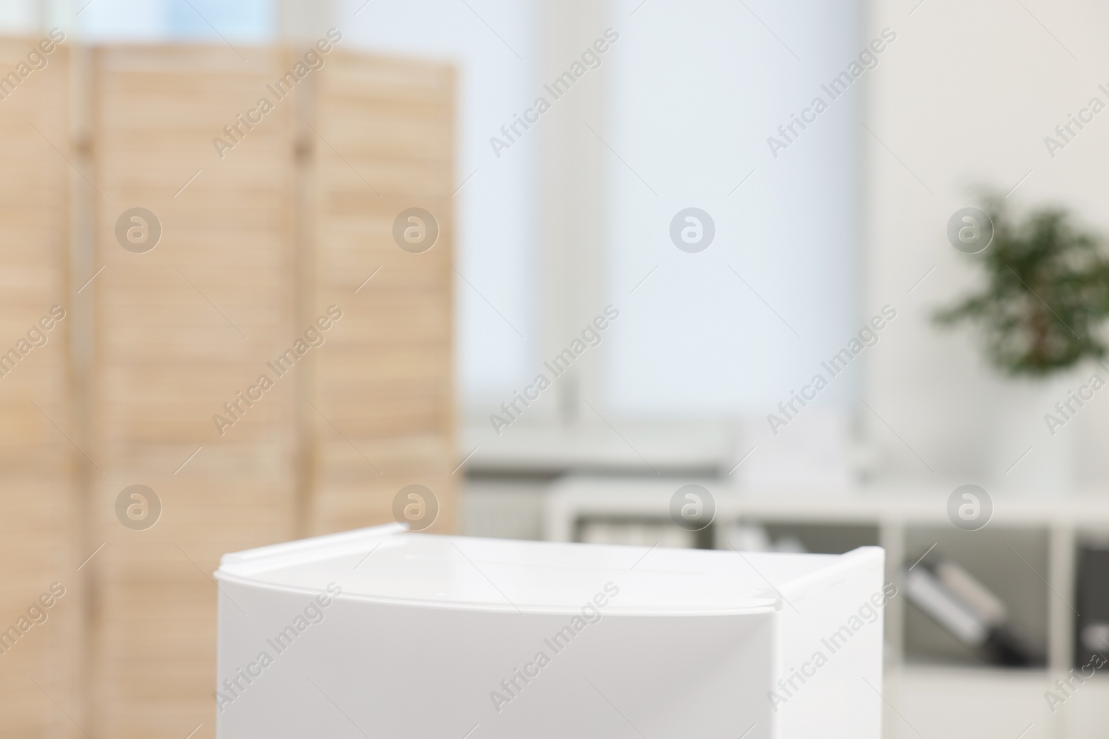 Photo of White ballot box on blurred background, closeup. Space for text