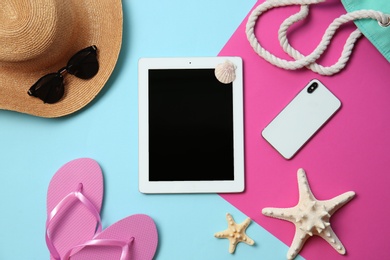 Flat lay composition with tablet and beach objects on color background