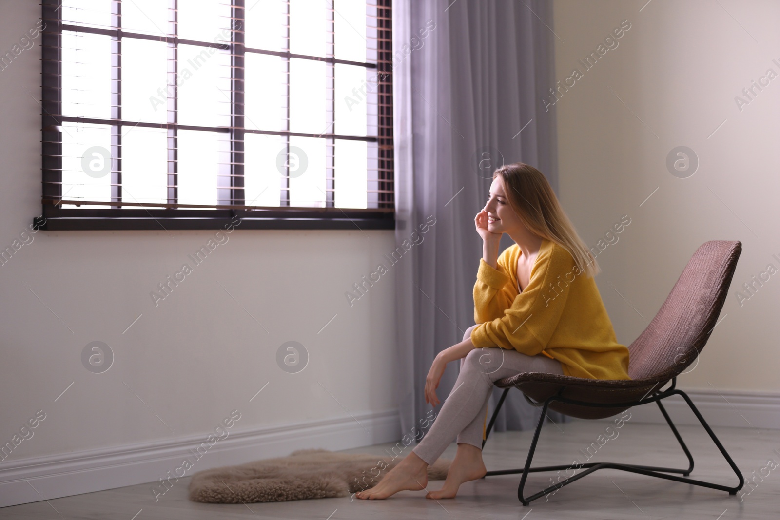 Photo of Young woman relaxing near window with blinds at home. Space for text