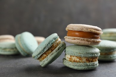 Photo of Different delicious macarons on grey table. Space for text