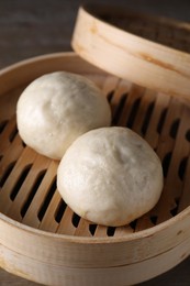 Delicious Chinese steamed buns in bamboo steamer on table, closeup