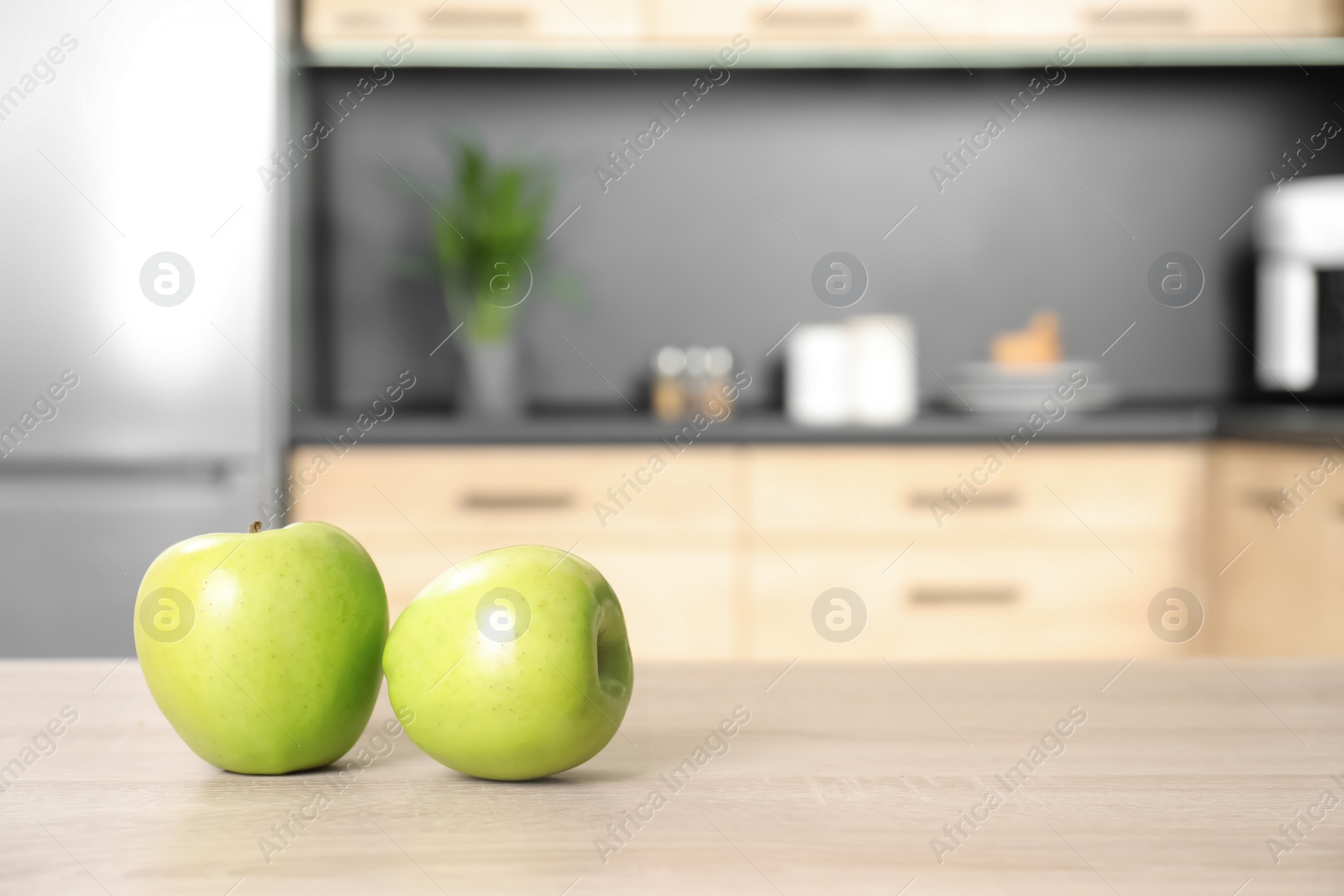 Photo of Fresh green apples on wooden table in kitchen. Space for text