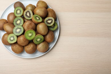Photo of Fresh ripe kiwis on light wooden table, top view. Space for text
