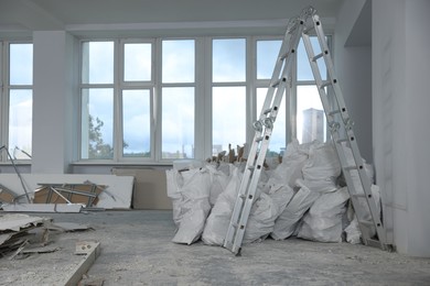 Used building materials and stepladder in room prepared for renovation