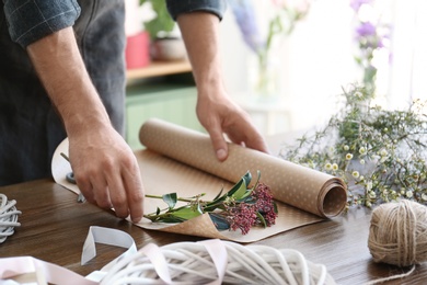 Photo of Male florist creating beautiful bouquet at table, closeup