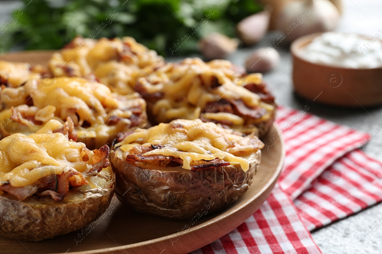 Photo of Plate of baked potatoes with cheese and bacon on table, closeup