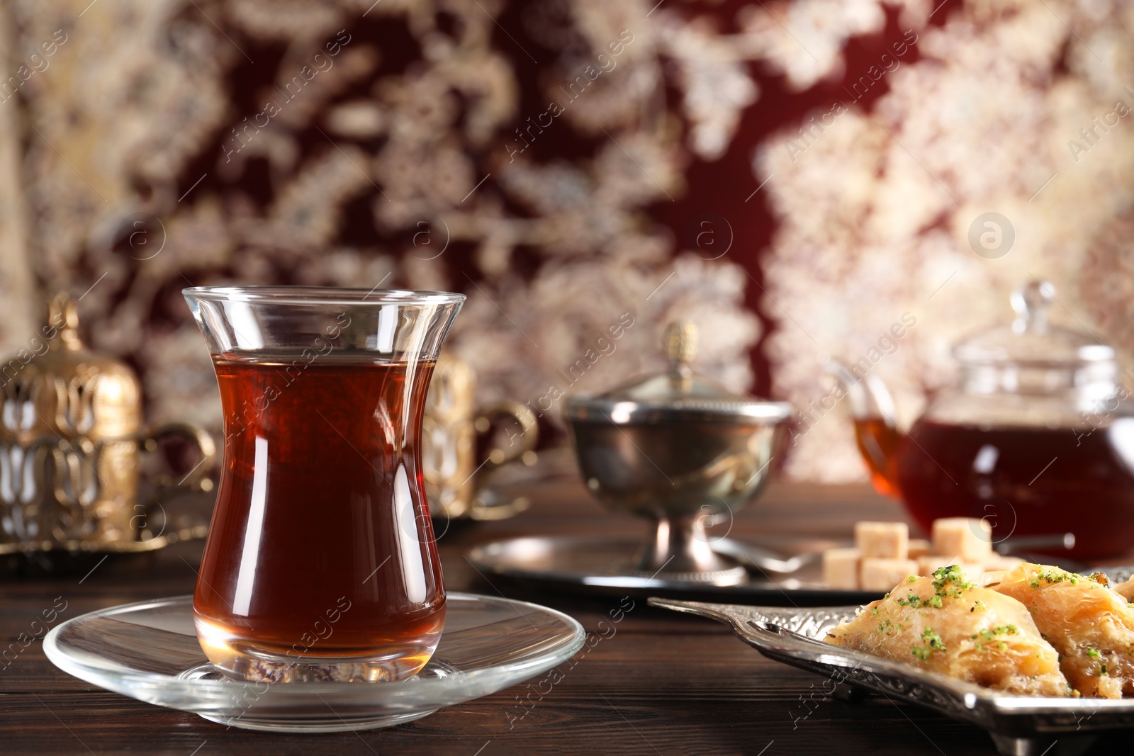 Photo of Traditional Turkish tea and sweets served in vintage tea set on wooden table. Space for text