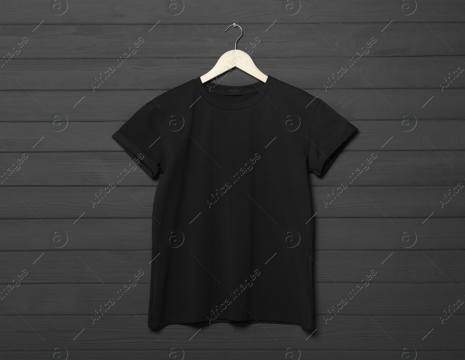 Photo of Hanger with stylish black T-shirt on gray wooden wall