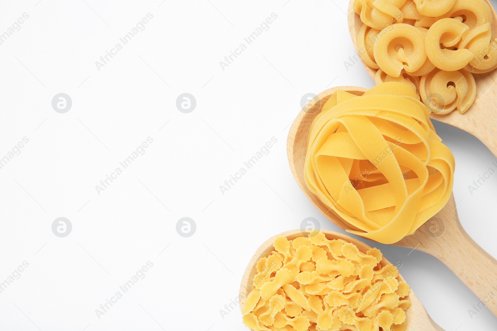 Photo of Different types of pasta in spoons on white background, flat lay. Space for text