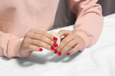 Woman removing nail polish at table, closeup