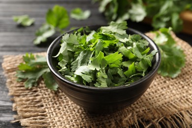 Photo of Cut fresh green cilantro in bowl on table, closeup