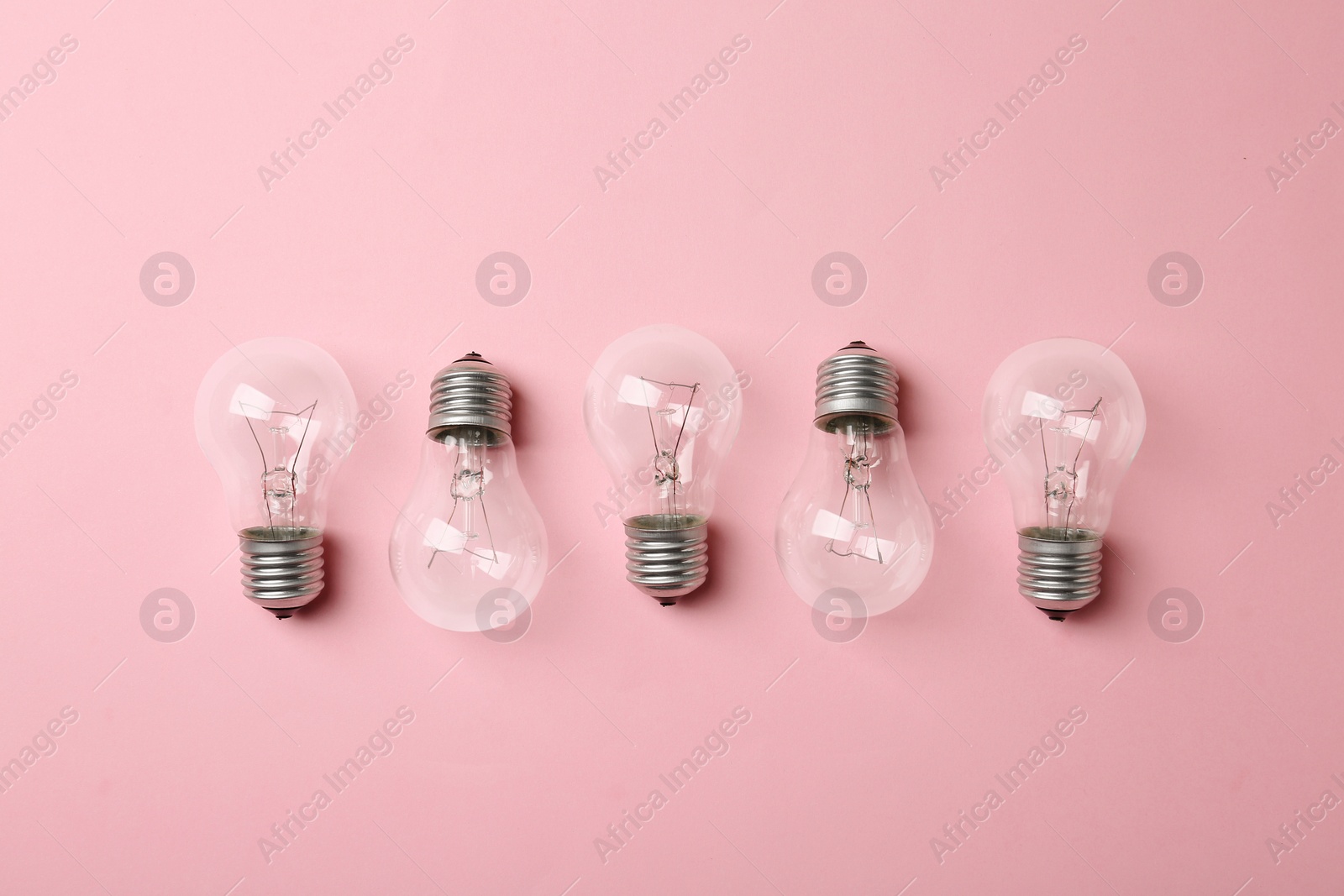 Photo of New incandescent lamp bulbs on pink background, top view