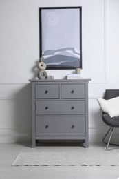 Stylish room interior with grey chest of drawers and beautiful picture