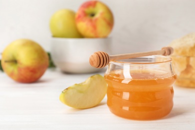 Photo of Jar of honey, apples and dipper on wooden table