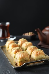 Photo of Delicious fresh baklava with chopped nuts on dark textured table, closeup. Eastern sweets