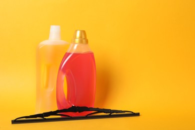 Bottles of windshield washer fluids and wiper on yellow background. Space for text