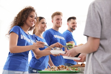 Photo of Volunteers serving food to poor people indoors